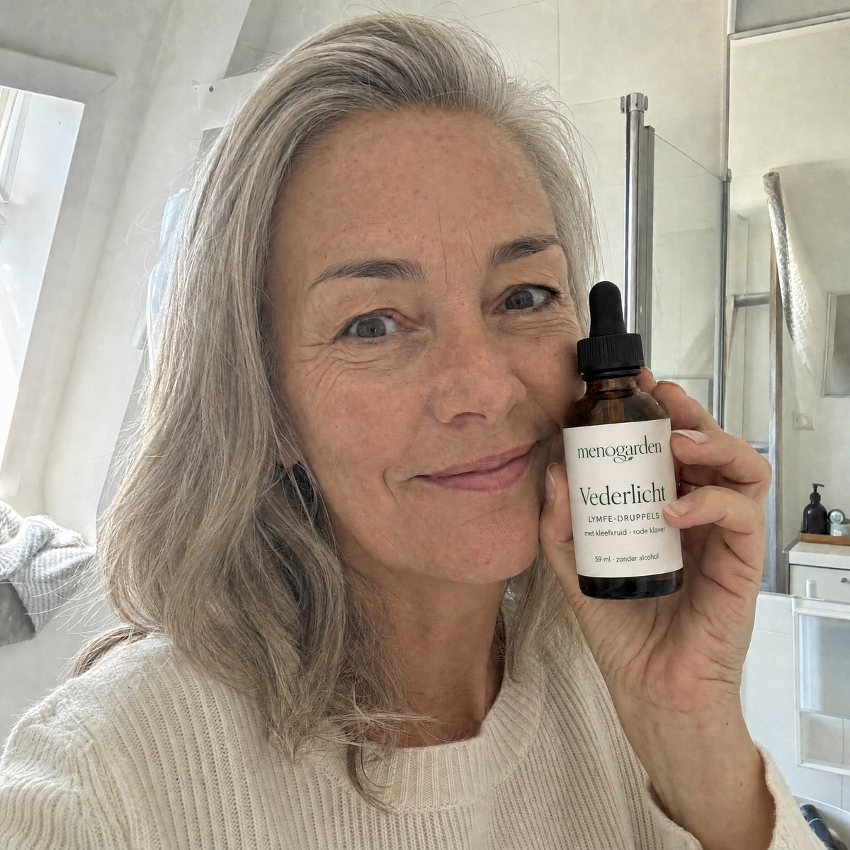 Vrouw met een fles Vederlicht in de badkamer